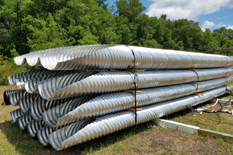 Stack of corrugated metal culverts CMP with elliptical mitered ends ready to be shipped